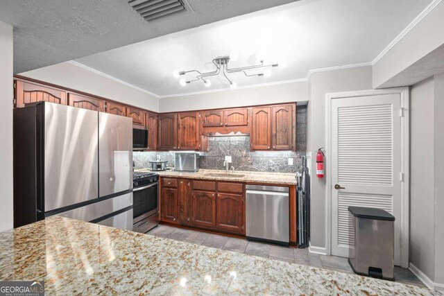 834 Lake Hollow Blvd SW, Marietta, GA 30064 - kitchen with appliances with stainless steel finishes, tasteful backsplash, ornamental molding, light stone counters, and brown cabinets