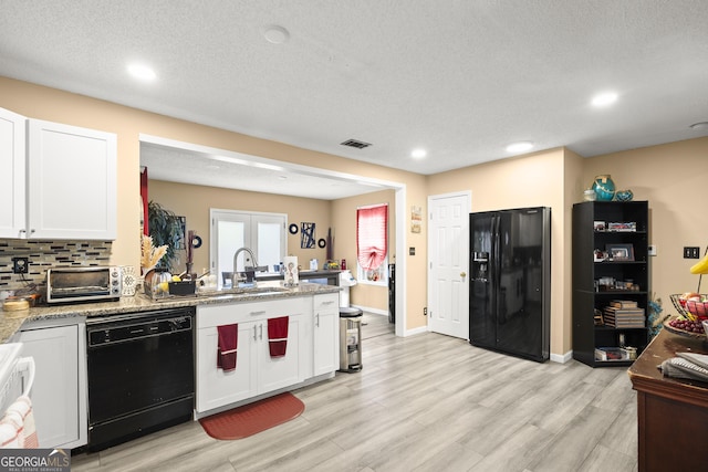7030 Kingston Ln, Mcdonough, GA 30253 - kitchen with black appliances, a peninsula, white cabinets, light wood-type flooring, and light stone countertops