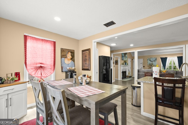 7030 Kingston Ln, Mcdonough, GA 30253 - dining area with a fireplace, light wood-style flooring, and recessed lighting