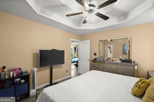 7030 Kingston Ln, Mcdonough, GA 30253 - bedroom with a tray ceiling, wood finished floors, ceiling fan, and a textured ceiling
