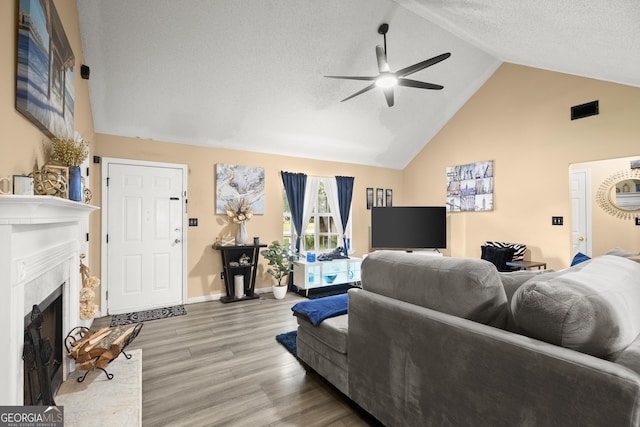 7030 Kingston Ln, Mcdonough, GA 30253 - living area featuring a ceiling fan, a fireplace with raised hearth, light wood-style floors, high vaulted ceiling, and a textured ceiling