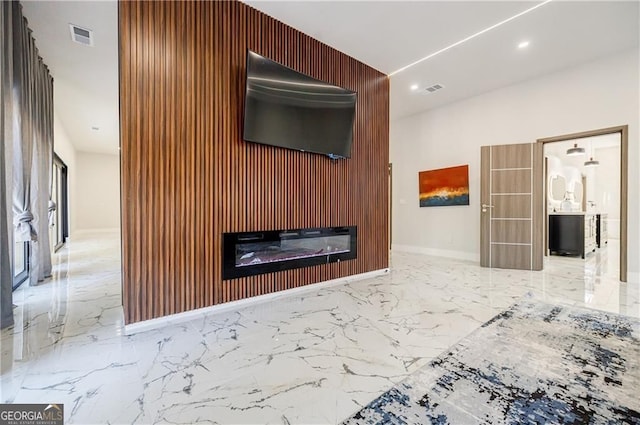 1812 Hunters Gln, Marietta, GA 30062 - unfurnished living room featuring marble tiled flooring, an accent wall, wood walls, a glass covered fireplace, and recessed lighting