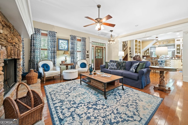 3349 Whitepath Rd, Ellijay, GA 30540 - living room featuring ornamental molding, a ceiling fan, a stone fireplace, wood-type flooring, and a chandelier