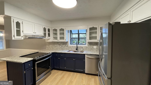 4710 Cedar Brook Dr SE, Conyers, GA 30094 - kitchen with appliances with stainless steel finishes, under cabinet range hood, light wood-style flooring, white cabinets, and a peninsula
