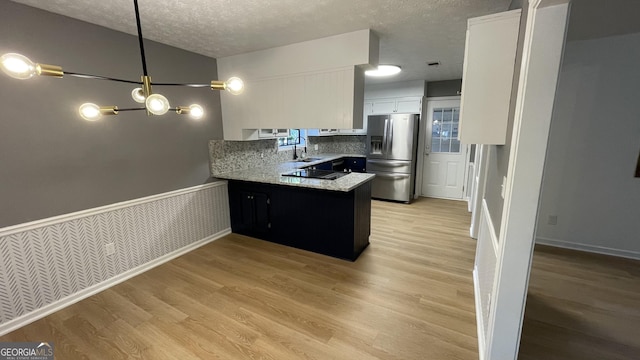 4710 Cedar Brook Dr SE, Conyers, GA 30094 - kitchen with stainless steel refrigerator with ice dispenser, a peninsula, white cabinets, a textured ceiling, and light wood-style floors