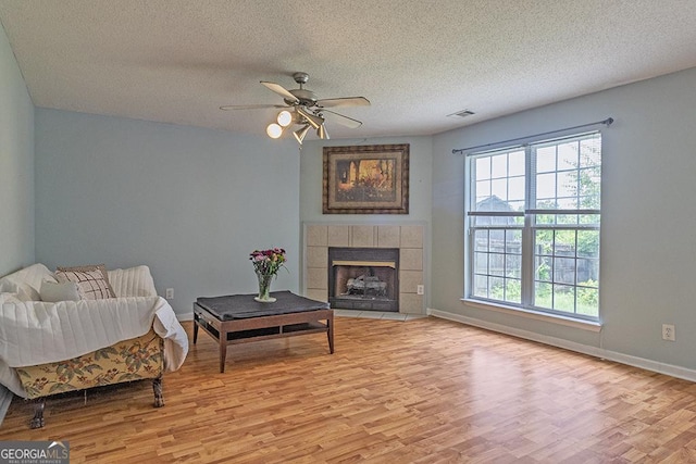 129 Larkspur Ln, Bonaire, GA 31005 - living area featuring light wood-style flooring, ceiling fan, a textured ceiling, and a fireplace