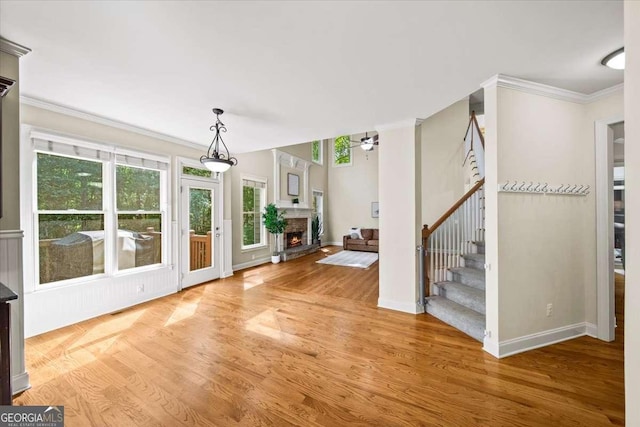 214 Davis Mill Rd, Ball Ground, GA 30107 - foyer featuring ornamental molding, stairway, light wood finished floors, a warm lit fireplace, and a ceiling fan