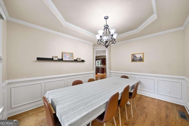 214 Davis Mill Rd, Ball Ground, GA 30107 - dining area with a chandelier, a raised ceiling, crown molding, wood finished floors, and a decorative wall