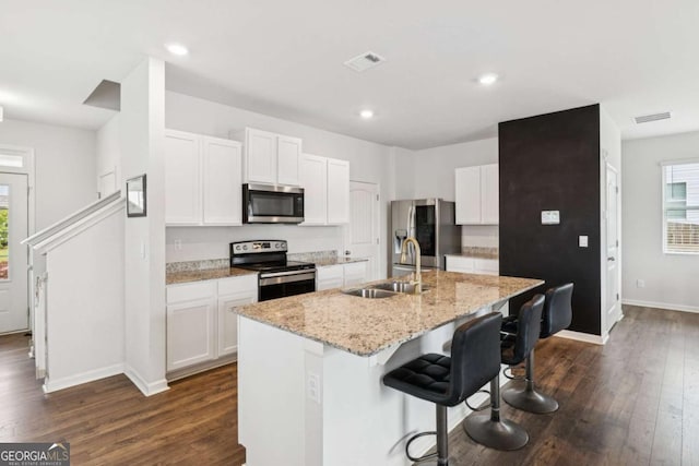 109 Grand Hickory Way, Dawsonville, GA 30534 - kitchen featuring stainless steel appliances, a breakfast bar, dark wood-type flooring, a center island with sink, and white cabinetry