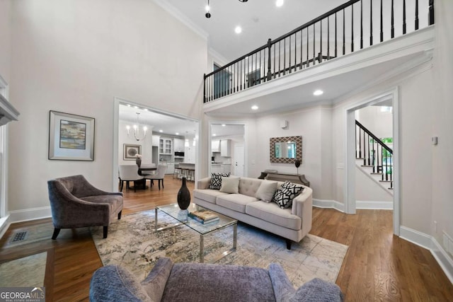 4544 Cavallon Way NW, Acworth, GA 30101 - living area featuring ornamental molding, stairway, a towering ceiling, wood finished floors, and a chandelier
