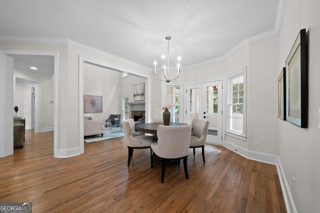4544 Cavallon Way NW, Acworth, GA 30101 - dining area with a chandelier, wood finished floors, a lit fireplace, and ornamental molding