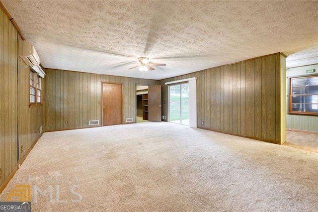 741 Greenhill Dr NE, Conyers, GA 30012 - spare room featuring a wall mounted air conditioner, ceiling fan, wood walls, carpet flooring, and a textured ceiling