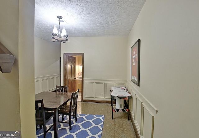 115 Shoal Creek Dr, Sharpsburg, GA 30277 - dining room featuring a chandelier, a decorative wall, a textured ceiling, wainscoting, and tile patterned floors