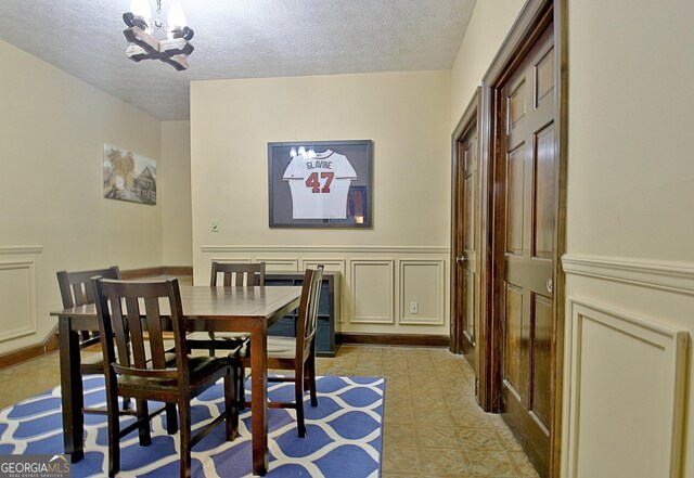 115 Shoal Creek Dr, Sharpsburg, GA 30277 - dining area with a chandelier, a textured ceiling, and a wainscoted wall