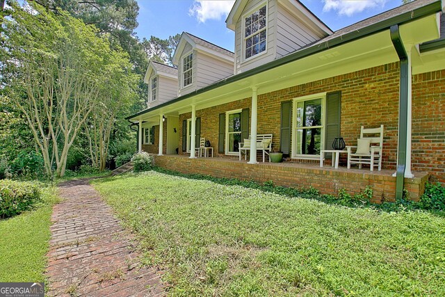 115 Shoal Creek Dr, Sharpsburg, GA 30277 - view of property exterior with brick siding, a porch, and a yard