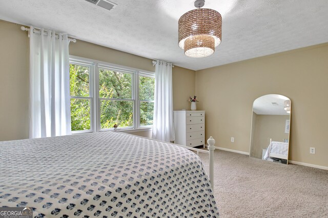 115 Shoal Creek Dr, Sharpsburg, GA 30277 - carpeted bedroom with arched walkways, a textured ceiling, and a chandelier