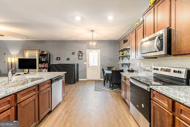 3350 Clawing Hawk Way, Douglasville, GA 30135 - kitchen with appliances with stainless steel finishes, light wood-style flooring, brown cabinetry, open floor plan, and light stone countertops