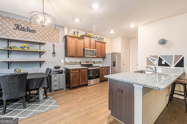 3350 Clawing Hawk Way, Douglasville, GA 30135 - kitchen with stainless steel appliances, light wood-style floors, a breakfast bar area, light stone counters, and a peninsula