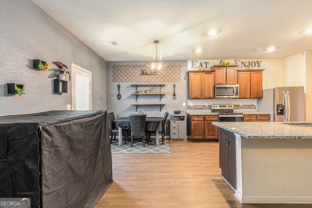 3350 Clawing Hawk Way, Douglasville, GA 30135 - kitchen featuring stainless steel appliances, brown cabinetry, light wood finished floors, light stone countertops, and pendant lighting