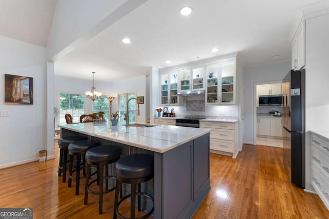 17 Shotgun Rd NW, Cartersville, GA 30121 - kitchen featuring stainless steel microwave, white cabinetry, backsplash, light wood finished floors, and a kitchen bar