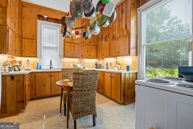 514 S Jefferson St, Washington, GA 30673 - kitchen featuring white electric stove, tasteful backsplash, brown cabinets, and light countertops