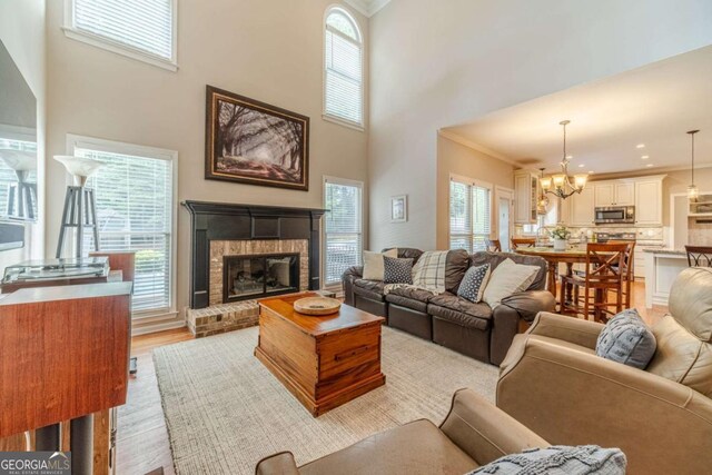 1461 Radstone Dr, Lawrenceville, GA 30044 - living area with crown molding, a fireplace, light wood-type flooring, a towering ceiling, and a chandelier