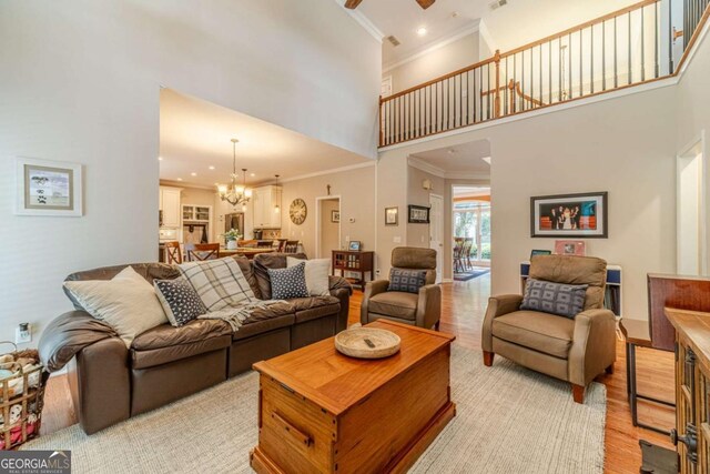 1461 Radstone Dr, Lawrenceville, GA 30044 - living room featuring light wood finished floors, a towering ceiling, crown molding, a chandelier, and a ceiling fan
