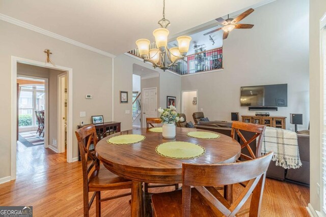 1461 Radstone Dr, Lawrenceville, GA 30044 - dining room with light wood-style floors, crown molding, stairway, a chandelier, and ceiling fan