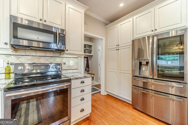 1461 Radstone Dr, Lawrenceville, GA 30044 - kitchen featuring stainless steel appliances, ornamental molding, white cabinets, decorative backsplash, and light wood-style floors