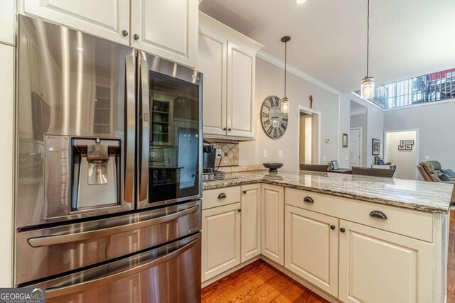 1461 Radstone Dr, Lawrenceville, GA 30044 - kitchen featuring stainless steel fridge with ice dispenser, a peninsula, pendant lighting, light stone counters, and ornamental molding