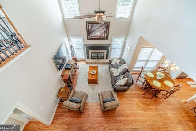 1461 Radstone Dr, Lawrenceville, GA 30044 - living room featuring a high ceiling, healthy amount of natural light, a ceiling fan, a brick fireplace, and wood finished floors