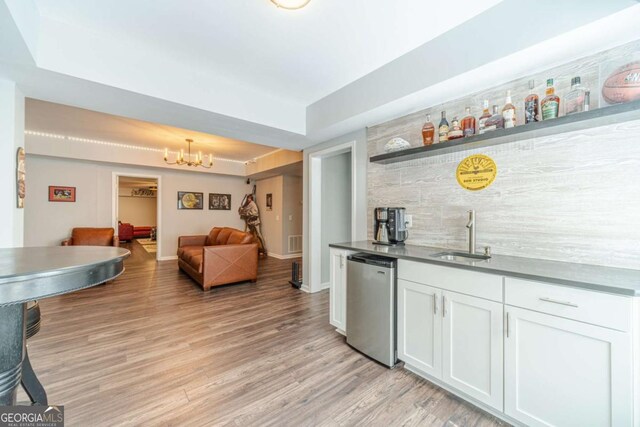1461 Radstone Dr, Lawrenceville, GA 30044 - indoor bar featuring light wood finished floors, stainless steel dishwasher, a chandelier, and tasteful backsplash