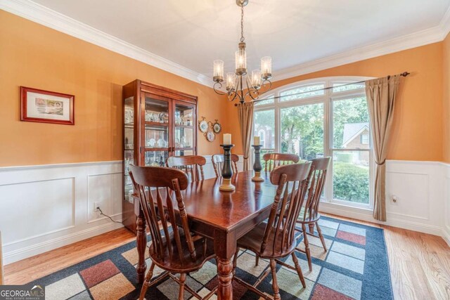 1461 Radstone Dr, Lawrenceville, GA 30044 - dining area with a chandelier, wood finished floors, ornamental molding, a wainscoted wall, and a decorative wall