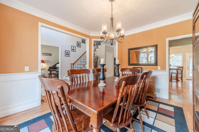 1461 Radstone Dr, Lawrenceville, GA 30044 - dining area featuring a chandelier, light wood-style floors, crown molding, a wainscoted wall, and stairway