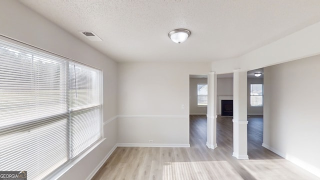 1001 Balsam Wood Trl, Villa Rica, GA 30180 - empty room with light wood finished floors, a textured ceiling, and a fireplace