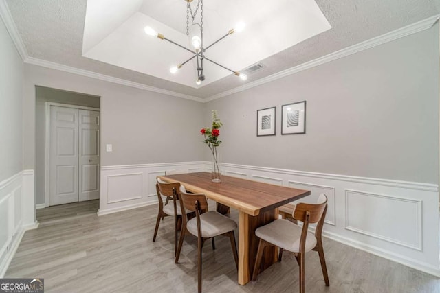 2895 Dominion Walk Ln, Snellville, GA 30078 - dining area featuring a chandelier, light wood finished floors, a decorative wall, a wainscoted wall, and a textured ceiling