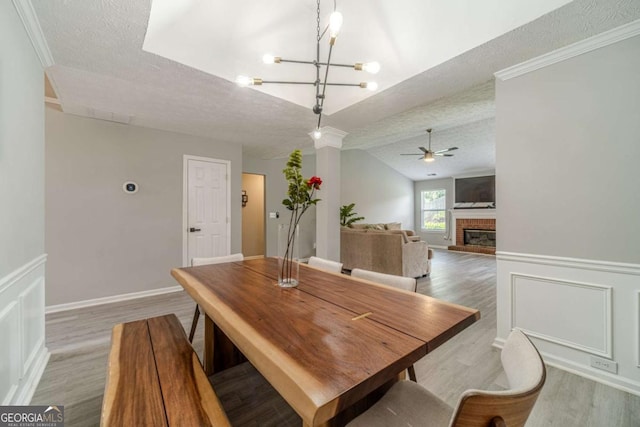 2895 Dominion Walk Ln, Snellville, GA 30078 - dining area featuring a textured ceiling, ceiling fan, wood finished floors, a fireplace, and a chandelier