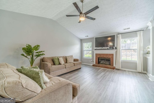 2895 Dominion Walk Ln, Snellville, GA 30078 - living room featuring wood finished floors, ceiling fan, a textured ceiling, a brick fireplace, and vaulted ceiling