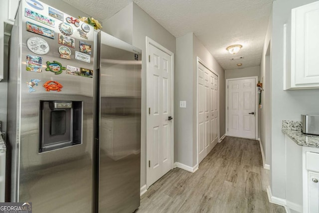2895 Dominion Walk Ln, Snellville, GA 30078 - kitchen featuring stainless steel fridge, light wood finished floors, white cabinets, a textured ceiling, and light stone counters