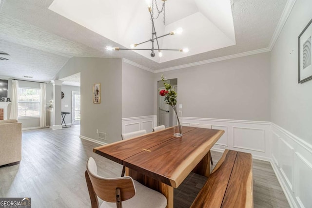 2895 Dominion Walk Ln, Snellville, GA 30078 - dining space featuring a chandelier, light wood-style flooring, wainscoting, a textured ceiling, and a decorative wall