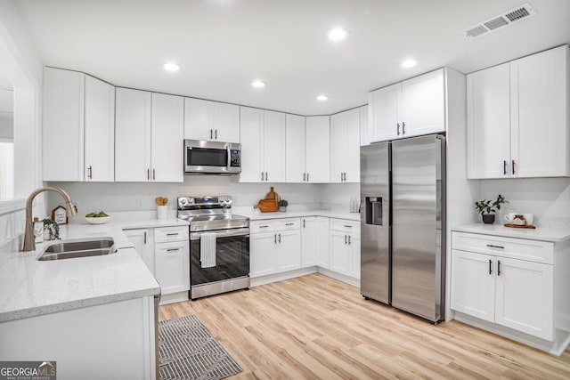 911 Oakland Dr SW, Atlanta, GA 30310 - kitchen with stainless steel appliances, light stone countertops, light wood finished floors, white cabinets, and recessed lighting