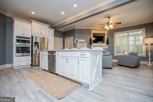 713 Birkdale Blvd, Carrollton, GA 30116 - kitchen featuring appliances with stainless steel finishes, open floor plan, crown molding, white cabinets, and an island with sink