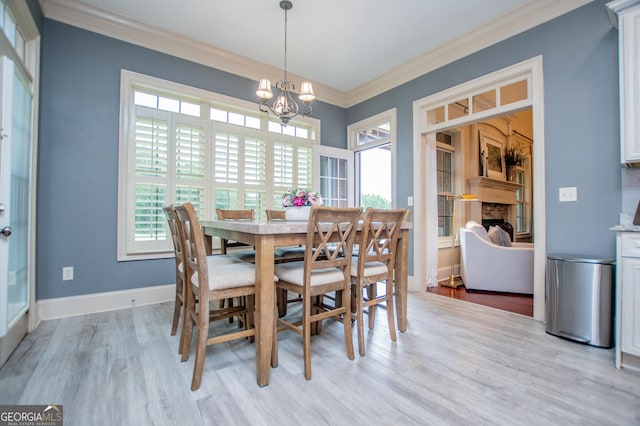 713 Birkdale Blvd, Carrollton, GA 30116 - dining space with a chandelier, light wood-style floors, a fireplace, and ornamental molding