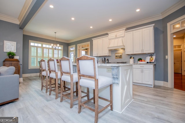 713 Birkdale Blvd, Carrollton, GA 30116 - kitchen with light wood finished floors, a chandelier, white cabinetry, a breakfast bar, and crown molding