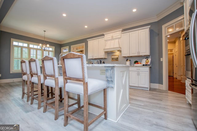 713 Birkdale Blvd, Carrollton, GA 30116 - kitchen with a chandelier, light wood finished floors, white cabinets, a kitchen breakfast bar, and ornamental molding