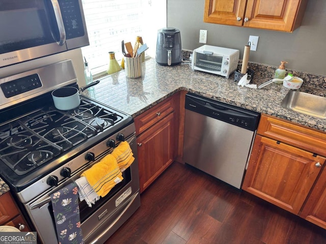 2479 Peachtree Rd NE Unit 1714, Atlanta, GA 30305 - kitchen with appliances with stainless steel finishes, dark wood-style floors, brown cabinetry, and dark stone countertops