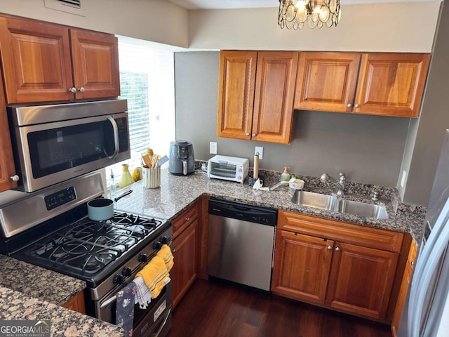 2479 Peachtree Rd NE Unit 1714, Atlanta, GA 30305 - kitchen featuring stainless steel appliances, brown cabinetry, dark wood-style flooring, dark stone counters, and a chandelier