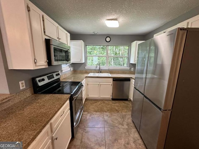 160 Lake Wellington Dr, Kingsland, GA 31548 - kitchen with stainless steel appliances, white cabinetry, a textured ceiling, and light tile patterned flooring