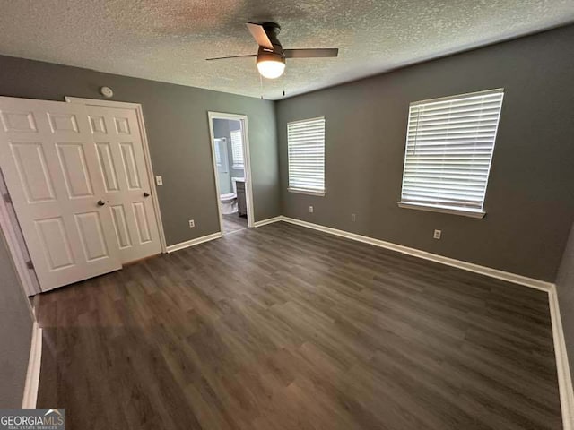 160 Lake Wellington Dr, Kingsland, GA 31548 - unfurnished bedroom with dark wood-style floors, a textured ceiling, a ceiling fan, connected bathroom, and a closet