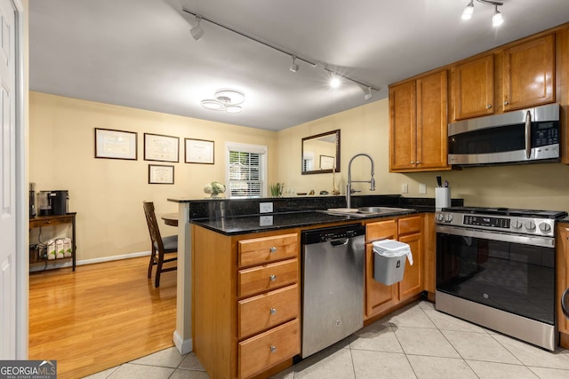 1445 Monroe Dr Unit 14B, Atlanta, GA 30324 - kitchen with stainless steel appliances, track lighting, a peninsula, and brown cabinets
